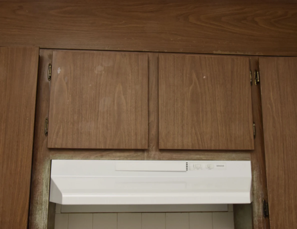 Closed wooden cabinet doors above a white stove hood.