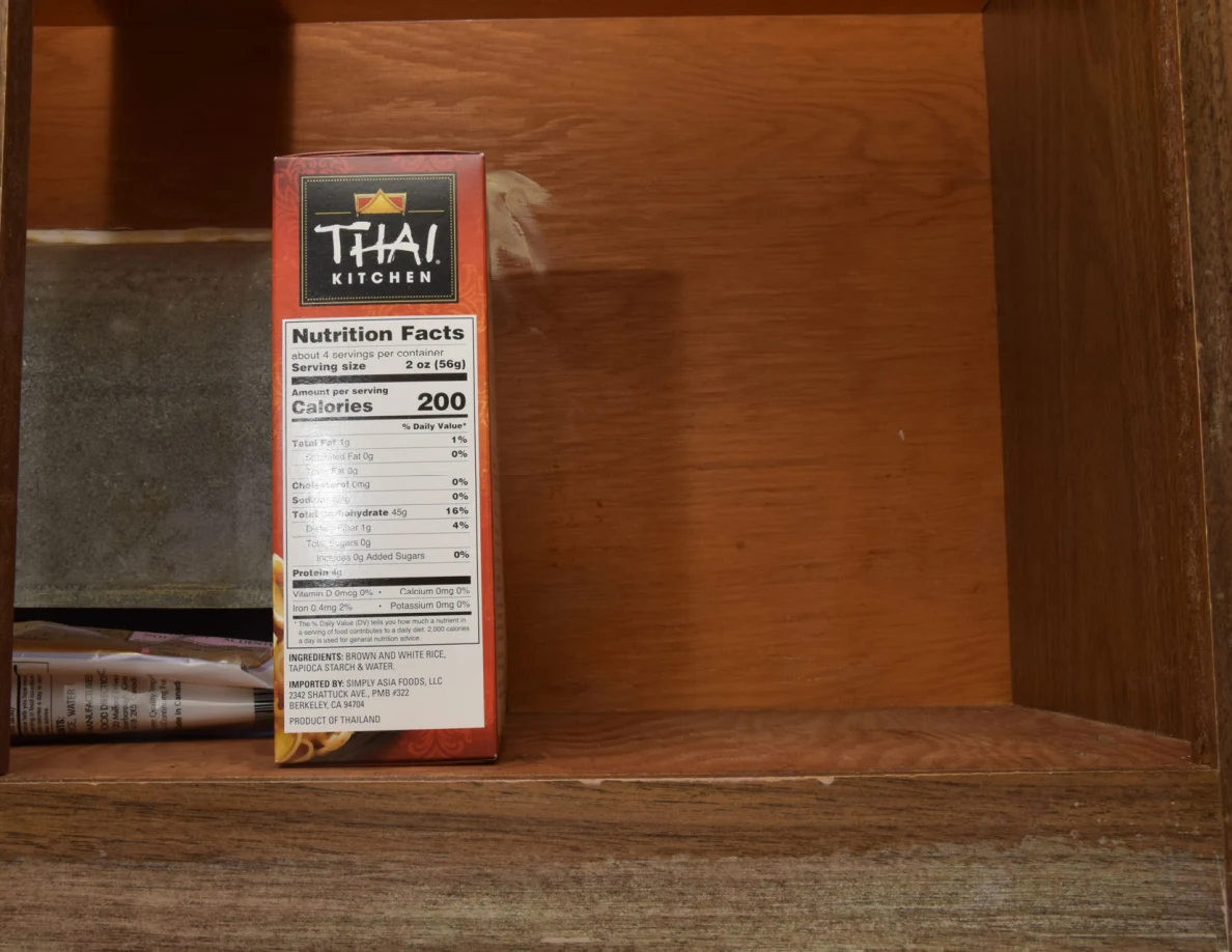 Thai Kitchen food box beside a metal duct on a cupboard shelf.