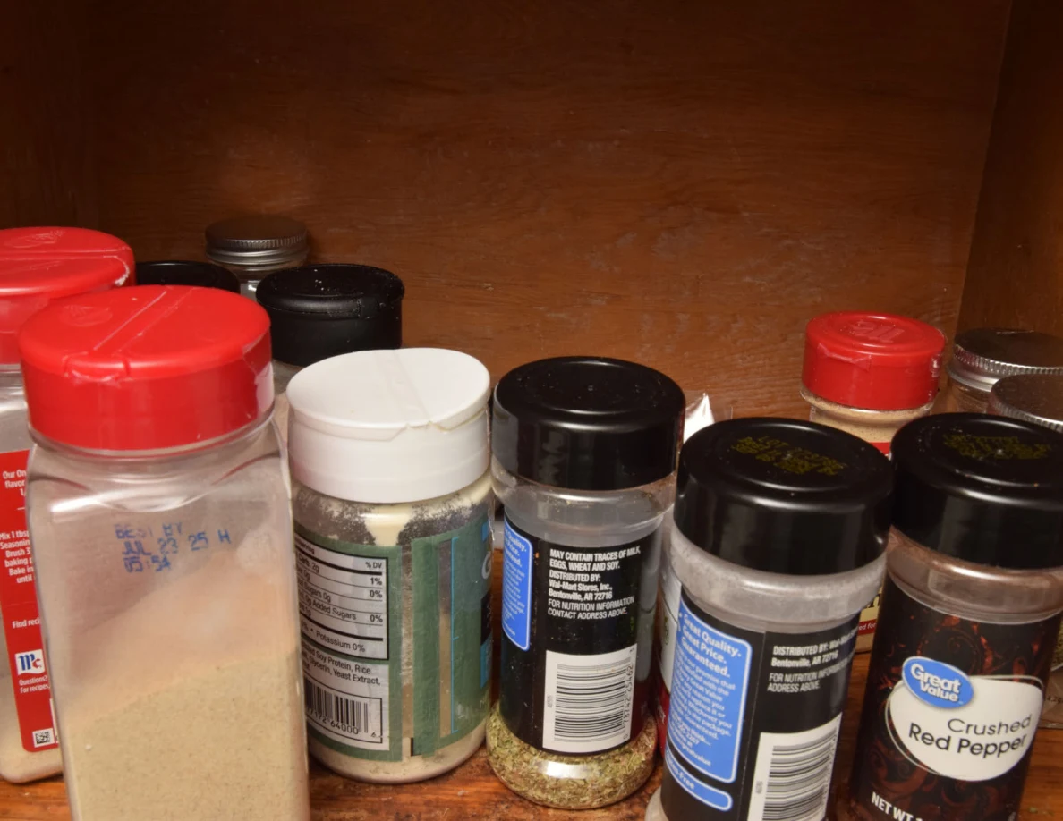 Close view of spice jars and seasoning containers with red, white and black lids.