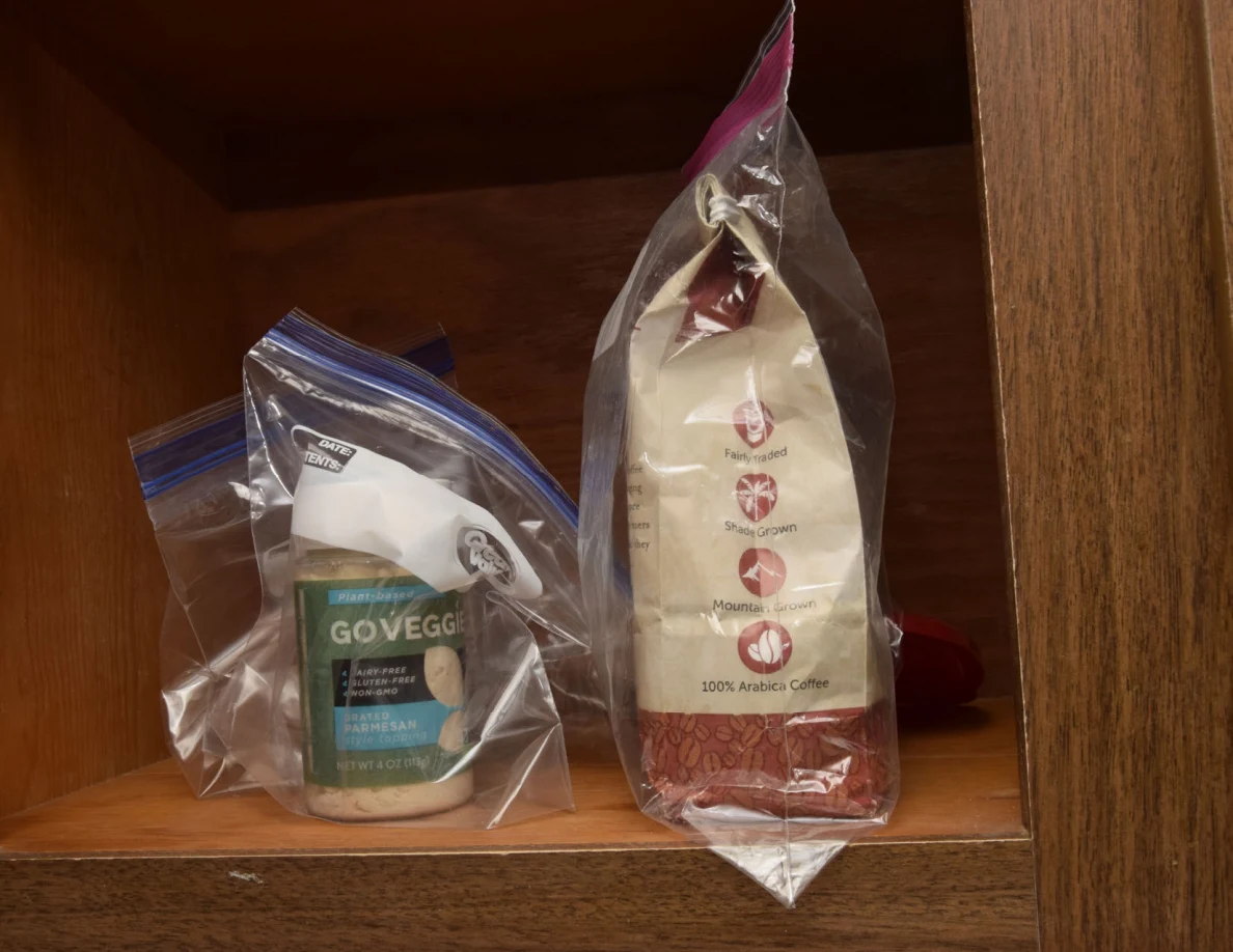 Bagged coffee and a small food container sealed inside clear plastic bags on a shelf.