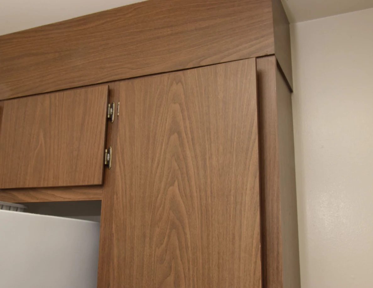 Upper wooden cupboard doors above and beside a refrigerator.