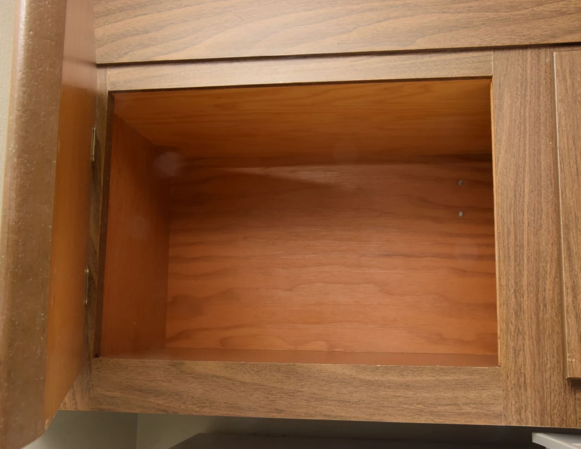 Open empty wooden cupboard above the refrigerator.