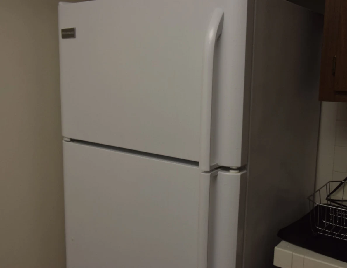 Closed white refrigerator and top freezer beside a kitchen counter.