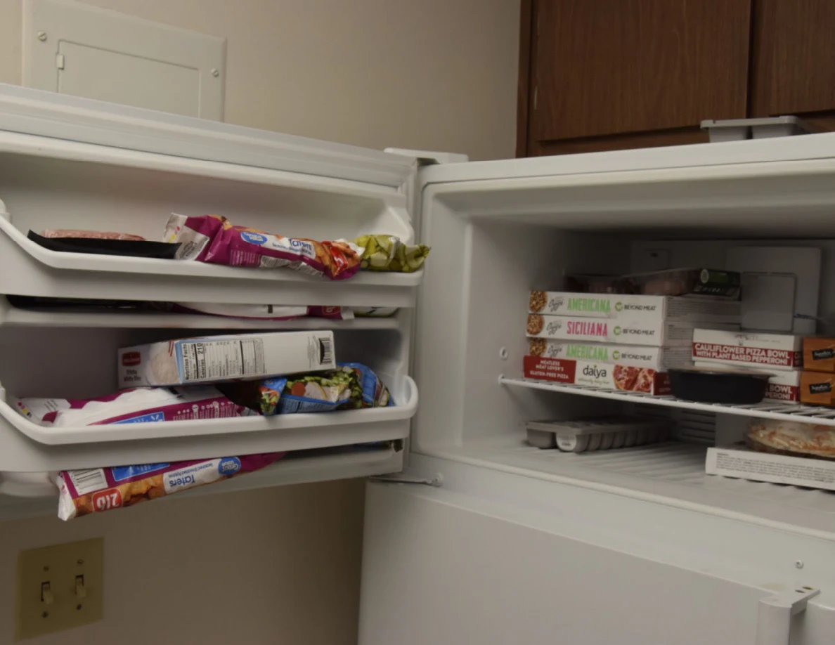 Open freezer with packaged frozen meals, bags of food and items in the door shelves.