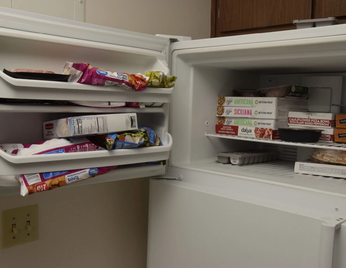 Angled view of an open freezer filled with boxed meals and bagged food.