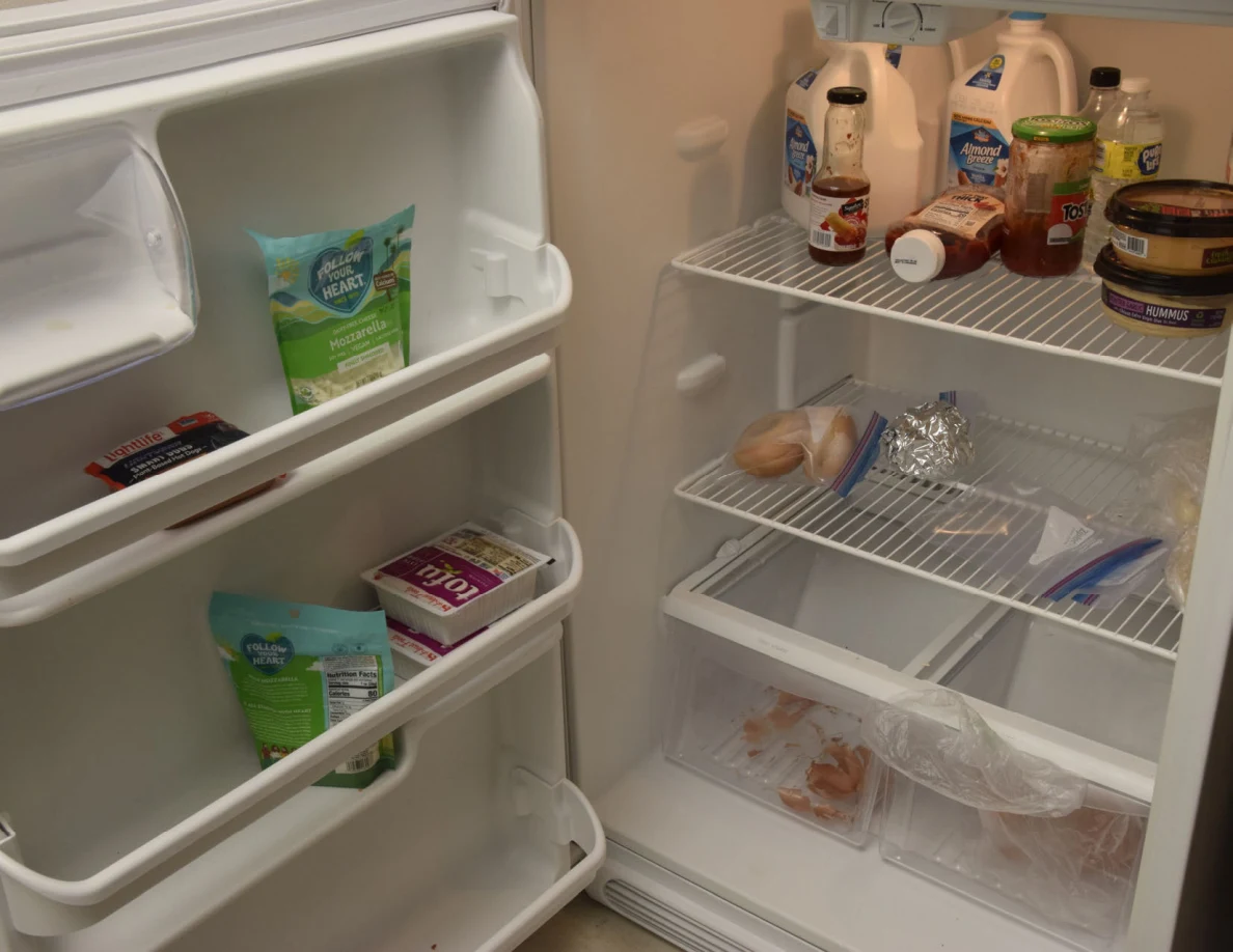 Open refrigerator with drink cartons, condiments, food bags and items in the door shelves and drawers.