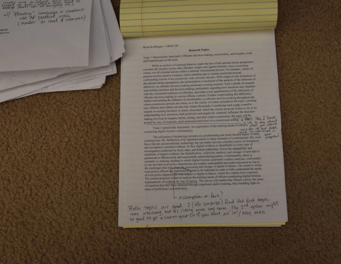 Closer view of a printed research-topic page with handwriting at the side and bottom, on carpet.