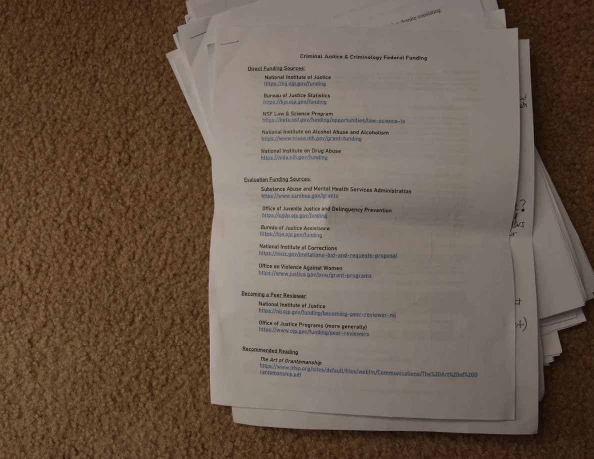 Printed criminal-justice and criminology funding-resource list on top of a stack of papers.