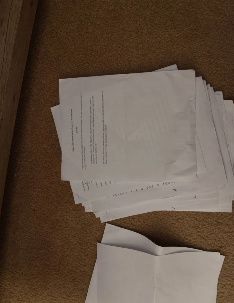Stack of printed pages beside loose folded sheets on carpet.