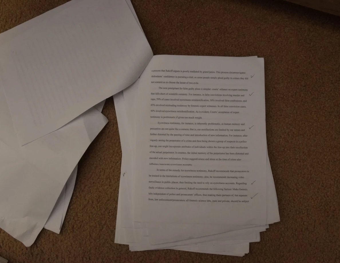 Stack of printed pages with check marks on the top sheet and a turned page at the upper left.