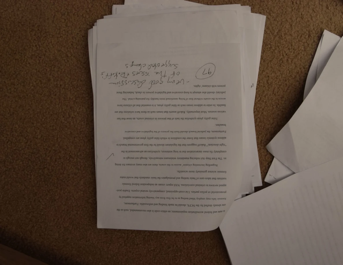 Upside-down printed page with a large handwritten comment and circled number on top of a stack.