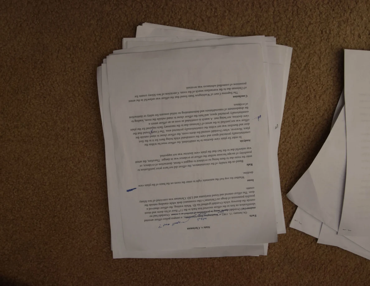 Upside-down printed page with small blue annotations, on a stack of papers.