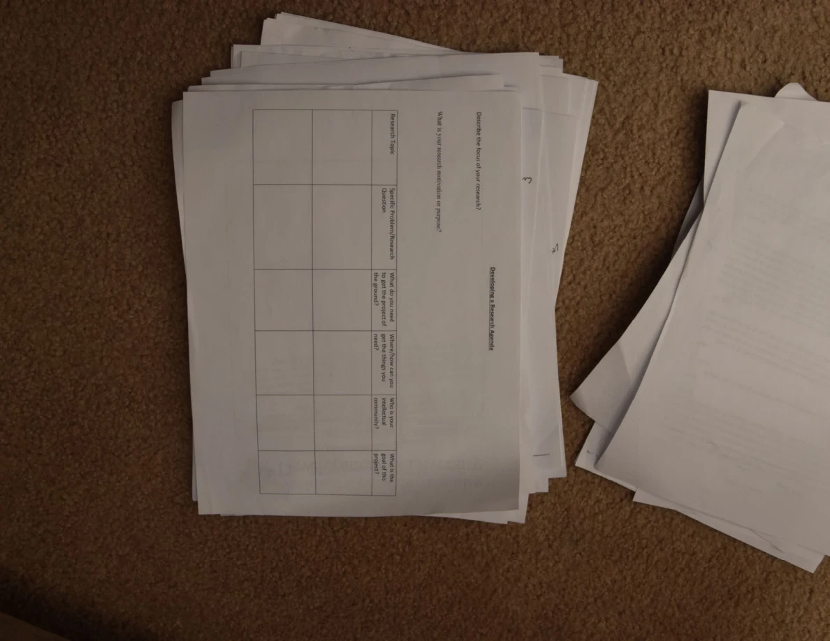 Printed evaluation table on top of a paper stack, photographed sideways on carpet.