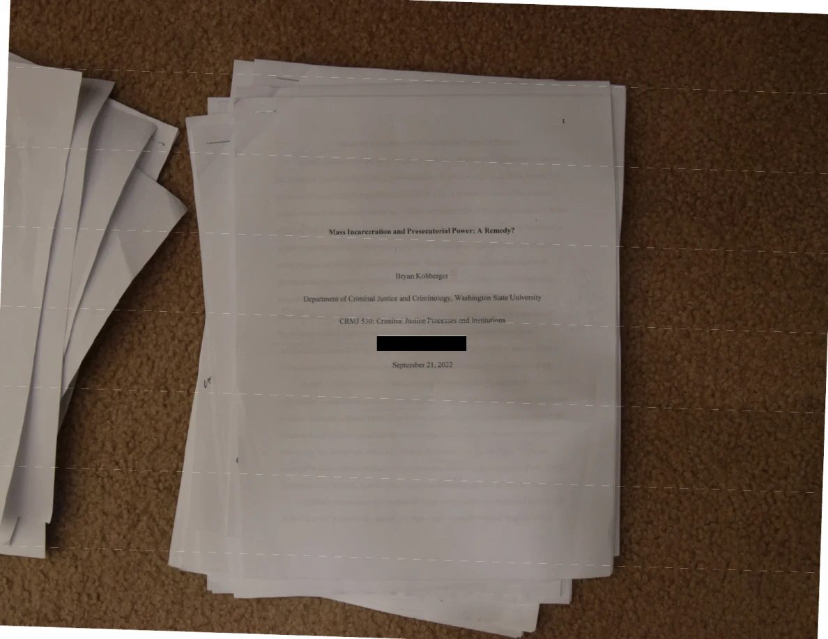Printed academic title page on a stack of papers, with a small black redaction below the course line.