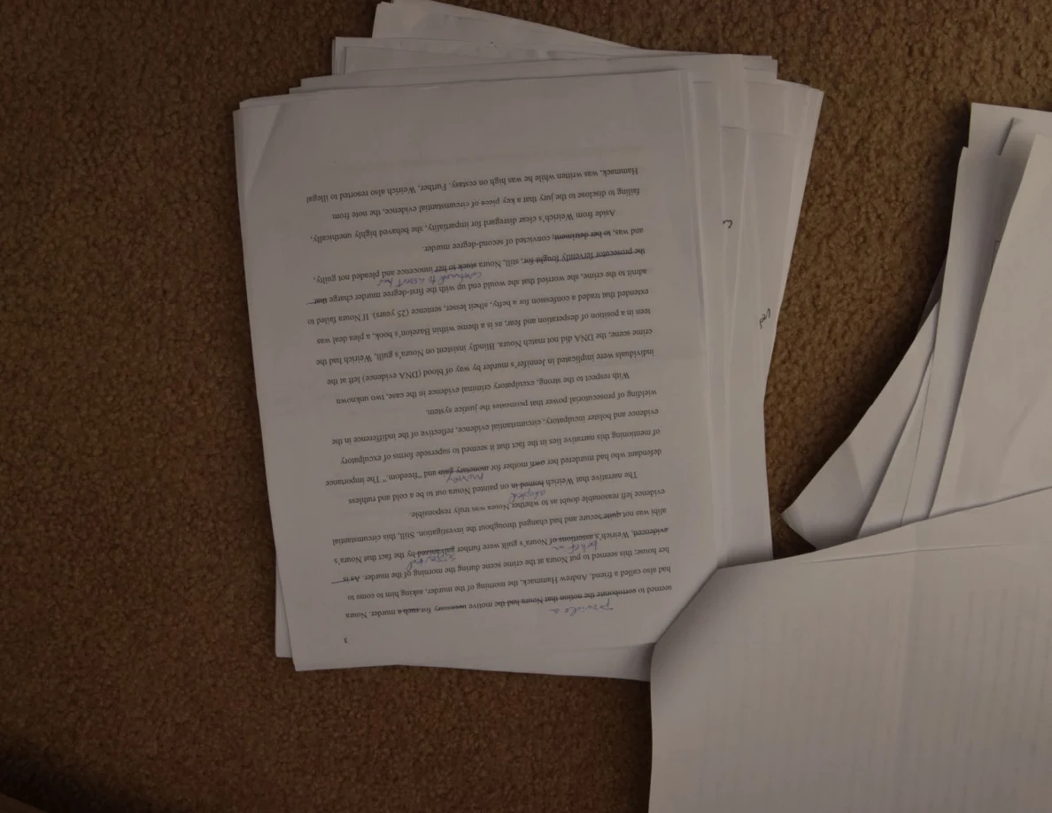 Upside-down printed essay page on a stack beside a turned sheet.