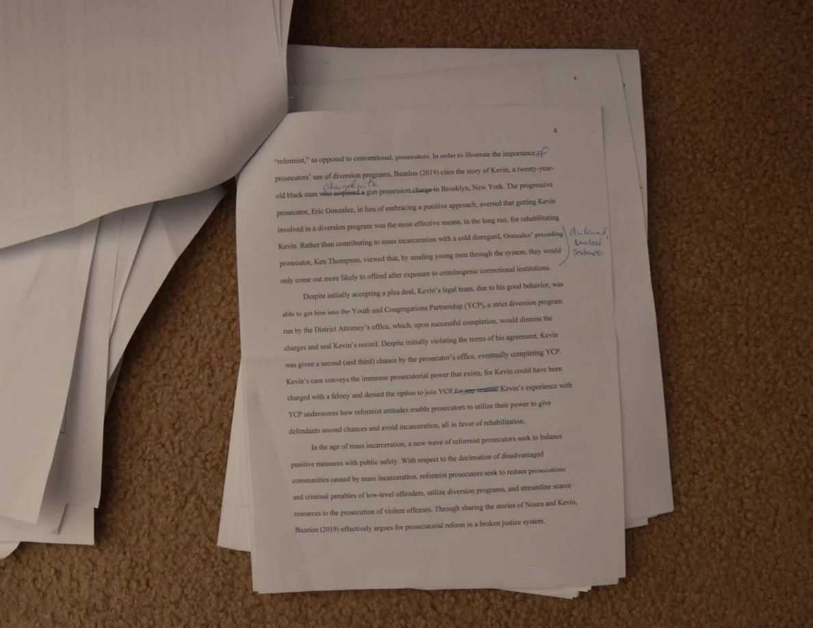 Annotated printed page resting on a stack, with a turned sheet at the upper left.