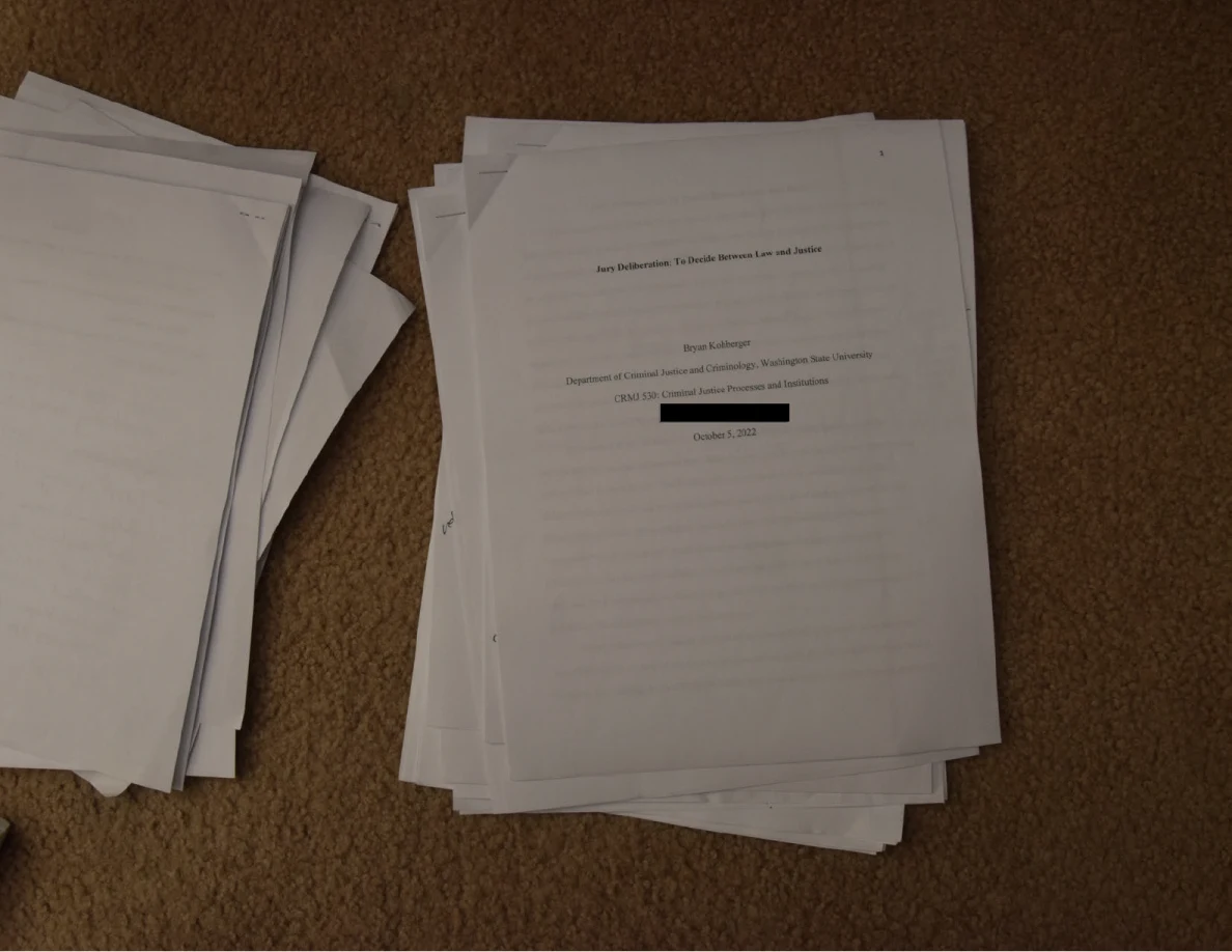 Academic title page on a stack of papers, with a black-redacted line.