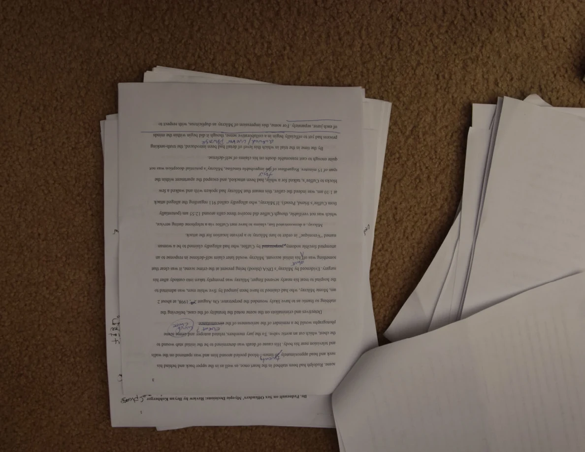Printed essay page photographed upside down, with handwriting near the lower edge.