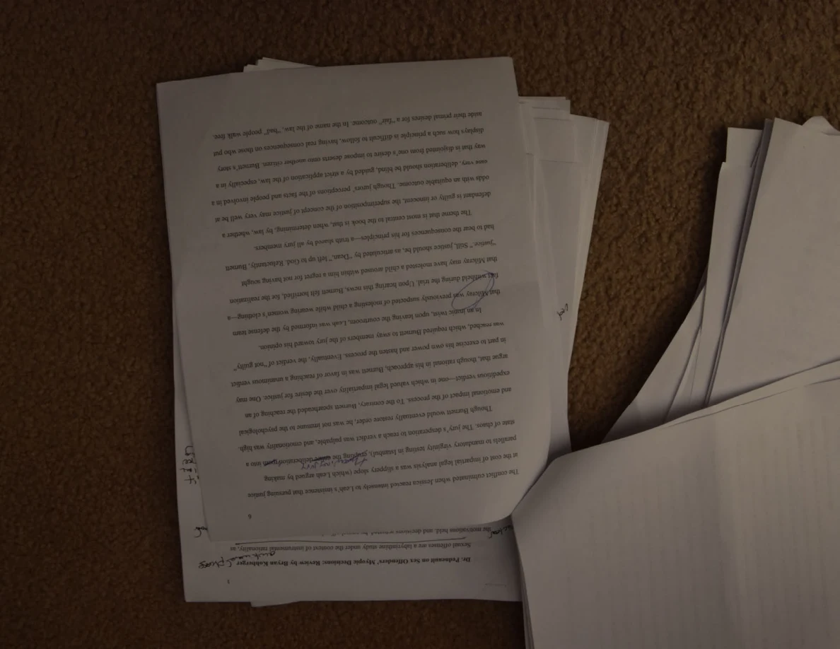 Upside-down essay page with handwritten corrections across the printed text.