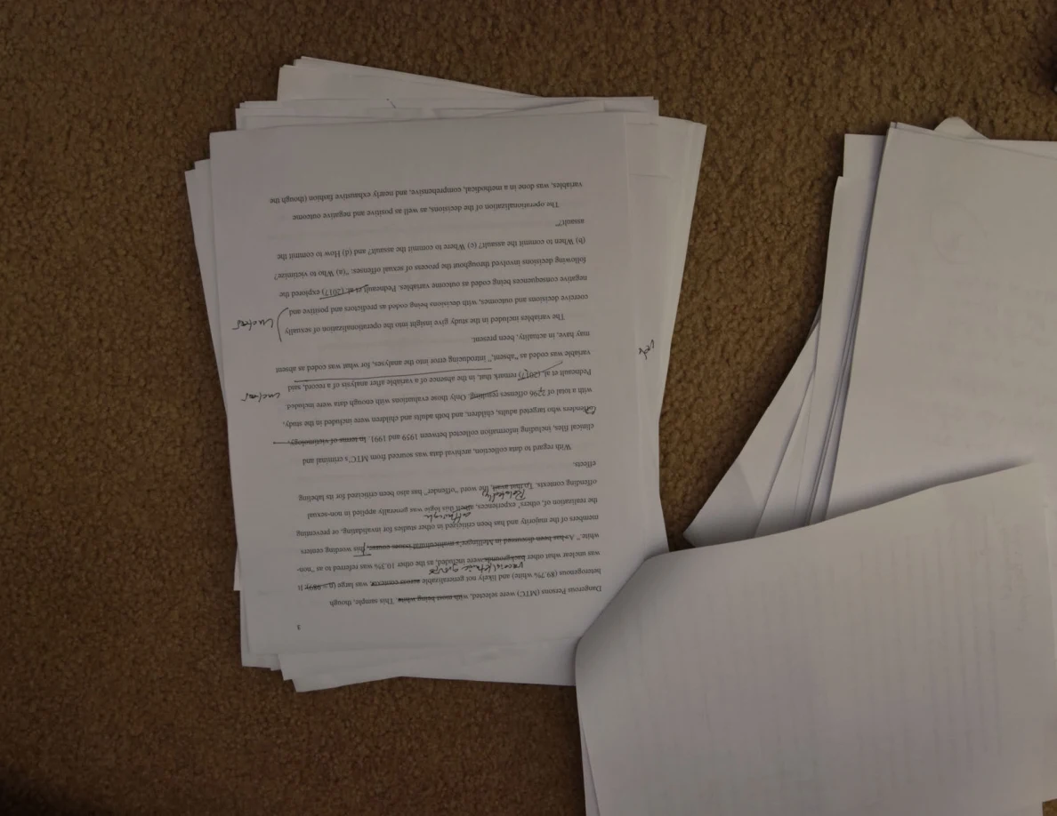 Printed page with handwritten margin notes, photographed upside down on carpet.