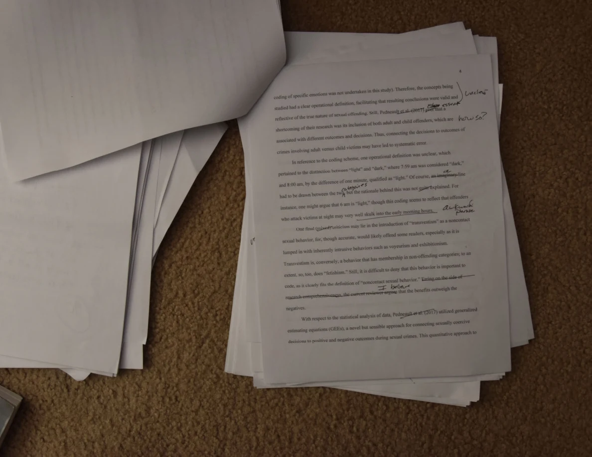 Annotated printed page with underlining and handwritten comments, beside a turned sheet.
