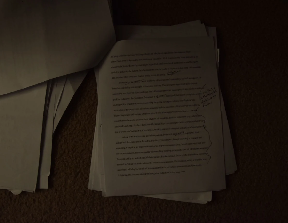 Dim view of a printed essay page with handwritten notes along the right margin.