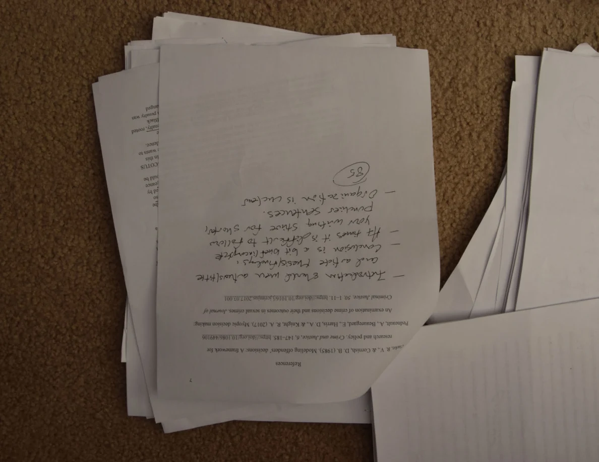Upside-down paper with large handwritten feedback and a circled number below printed paragraphs.