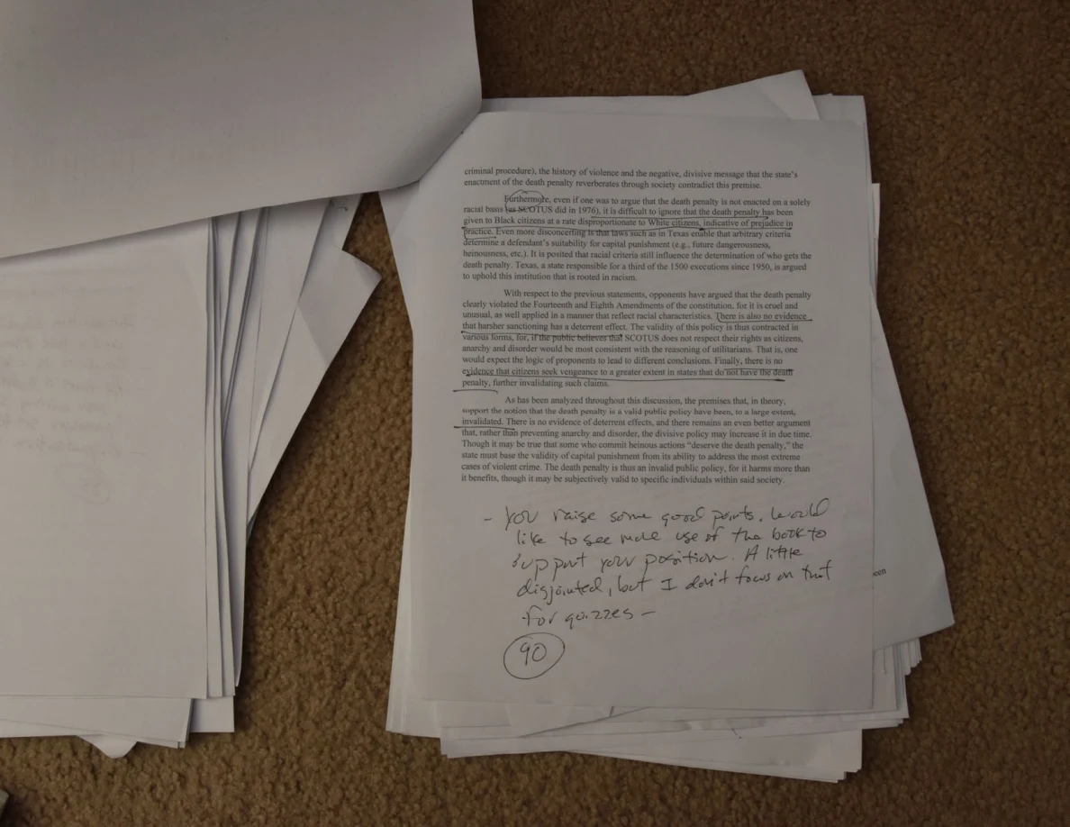 Printed essay page with handwritten feedback and a circled number near the bottom.