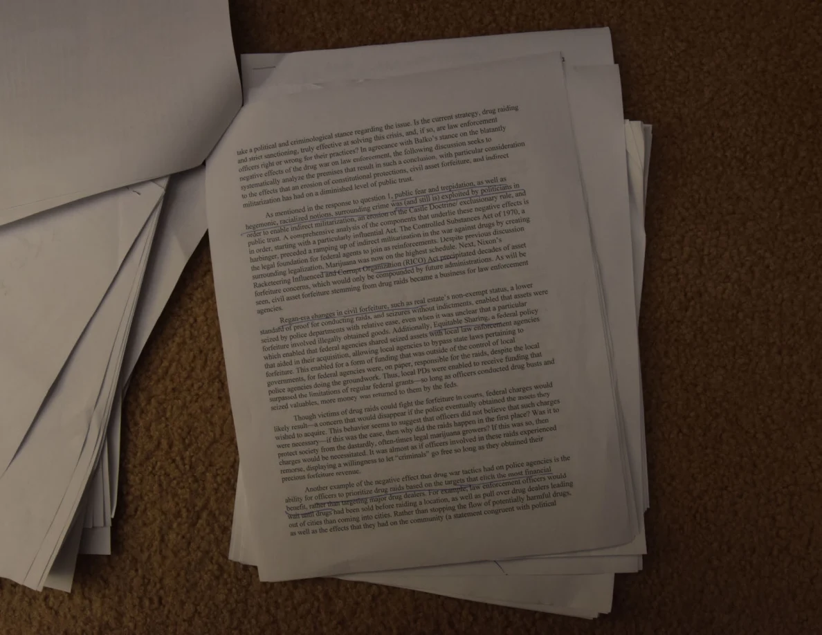 Printed essay page on a paper stack with a turned sheet at the upper left.