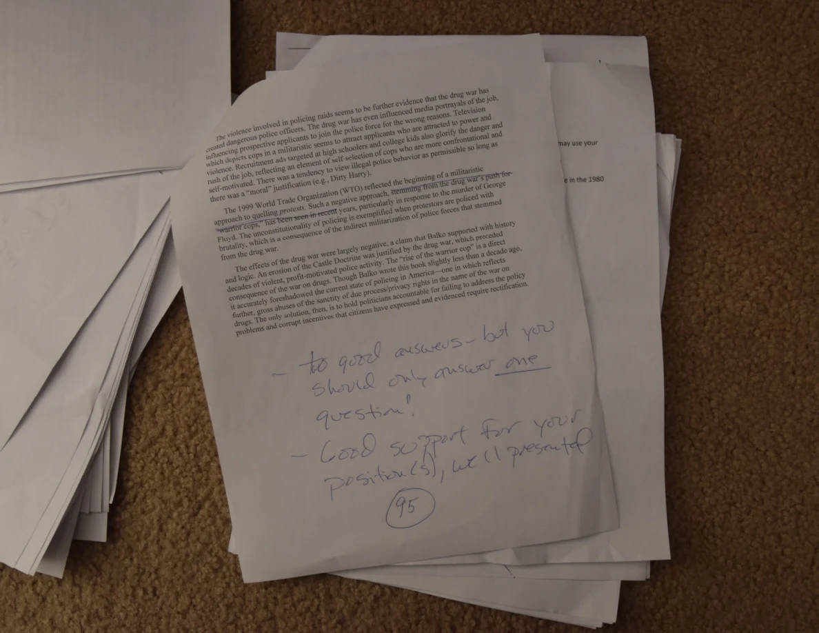 Printed essay page with large handwritten feedback and a circled number near the bottom.