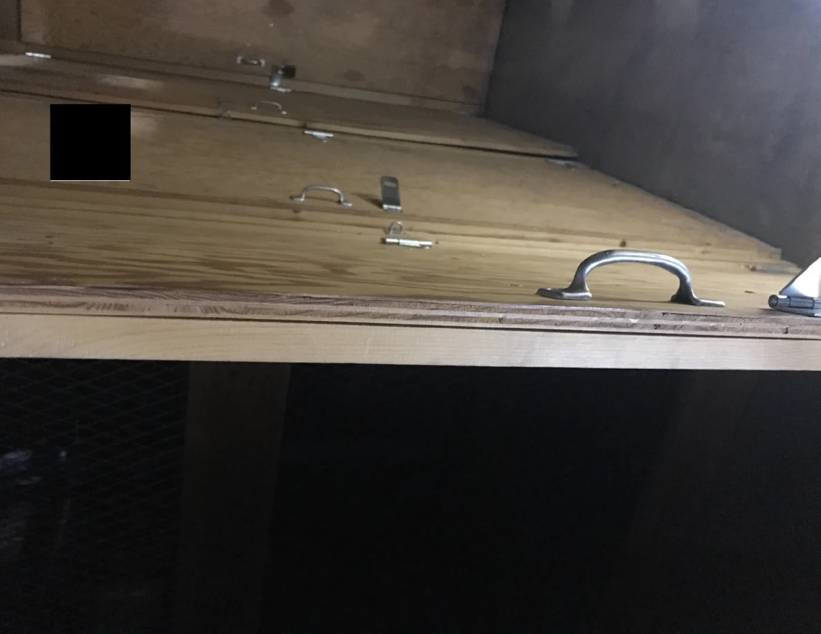 Low angled view of plywood panels with metal pull handles and hinged hasps.
