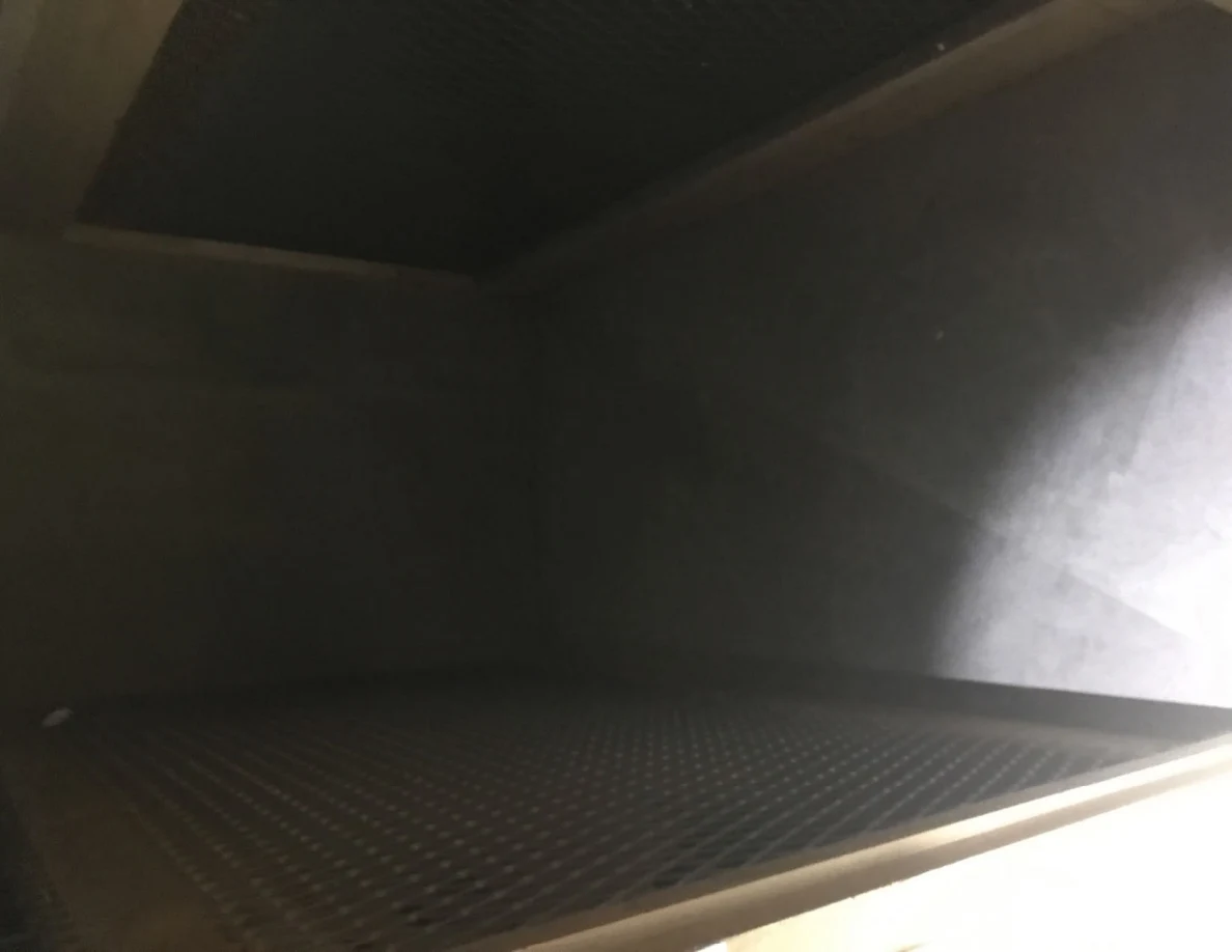 Dim interior of an empty compartment with mesh above and below, and gray walls.