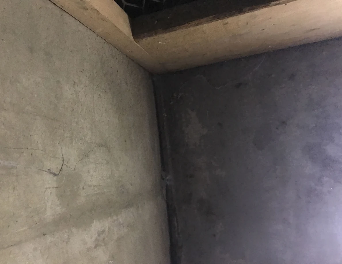 Close view of the corner where two gray walls meet below a wooden frame.