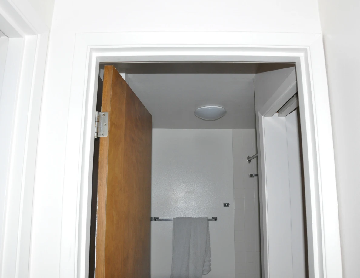 Upper bathroom doorway framing a round ceiling light and hanging gray towel.