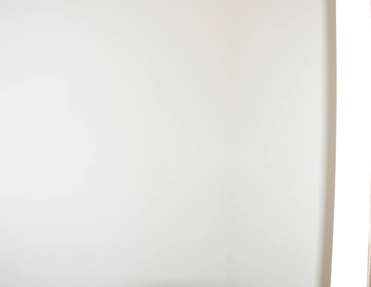 Close view of a pale wall with a vertical shadow along its edge.