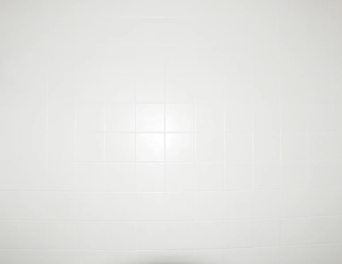 Close view of plain white square shower tiles.