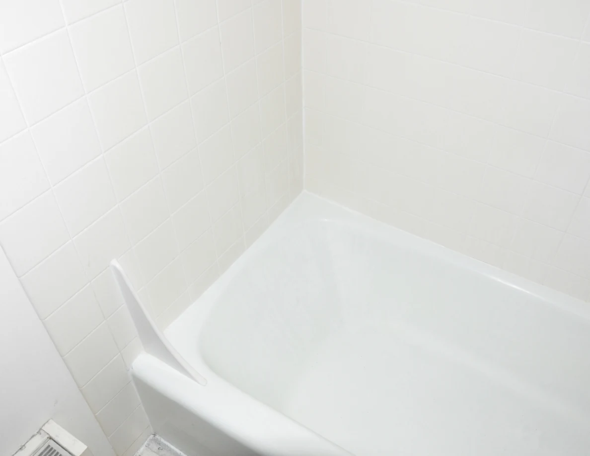 White bathtub end and tiled walls with a small upright splash guard.