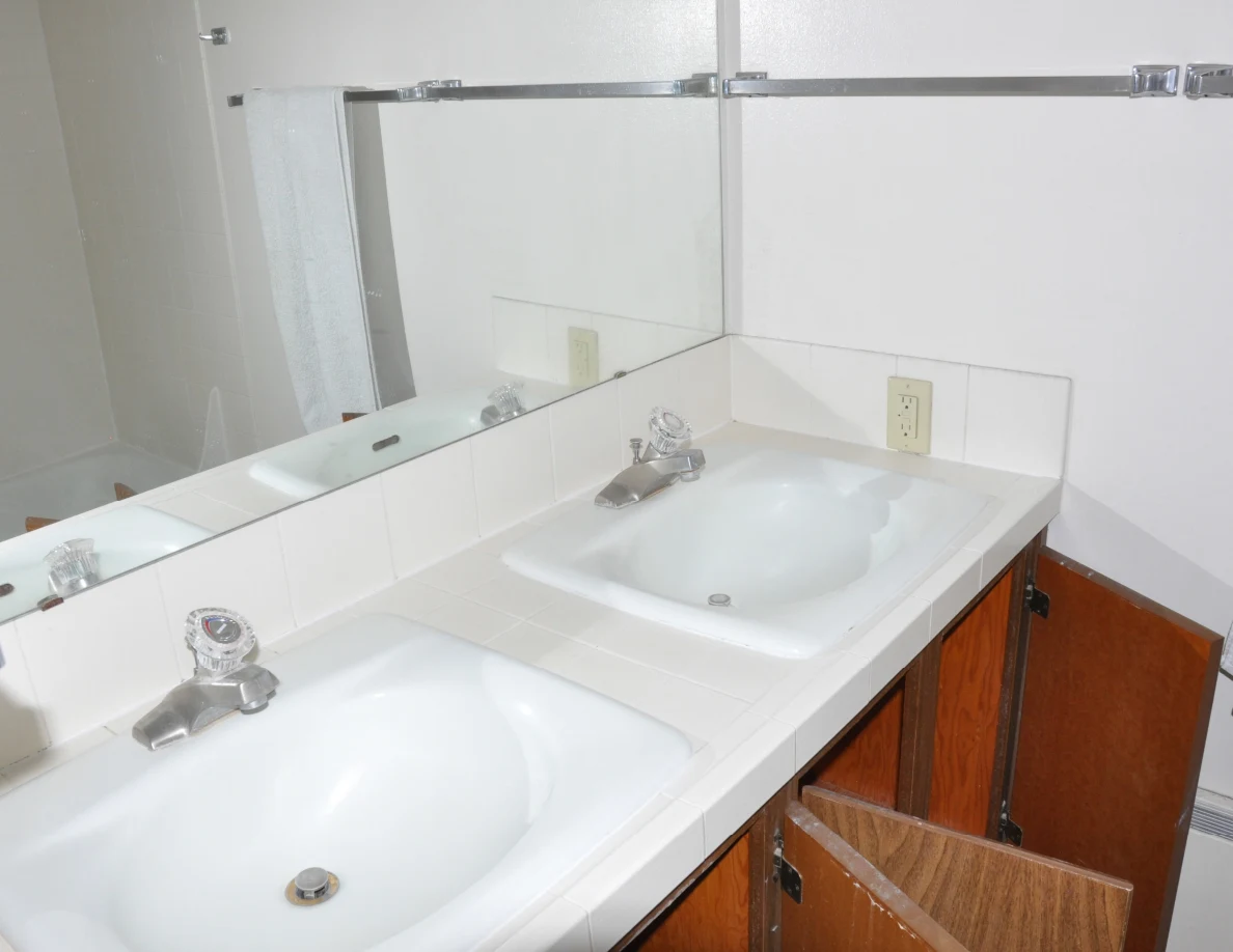 Double-sink bathroom vanity with a large mirror and open wooden cupboard doors.