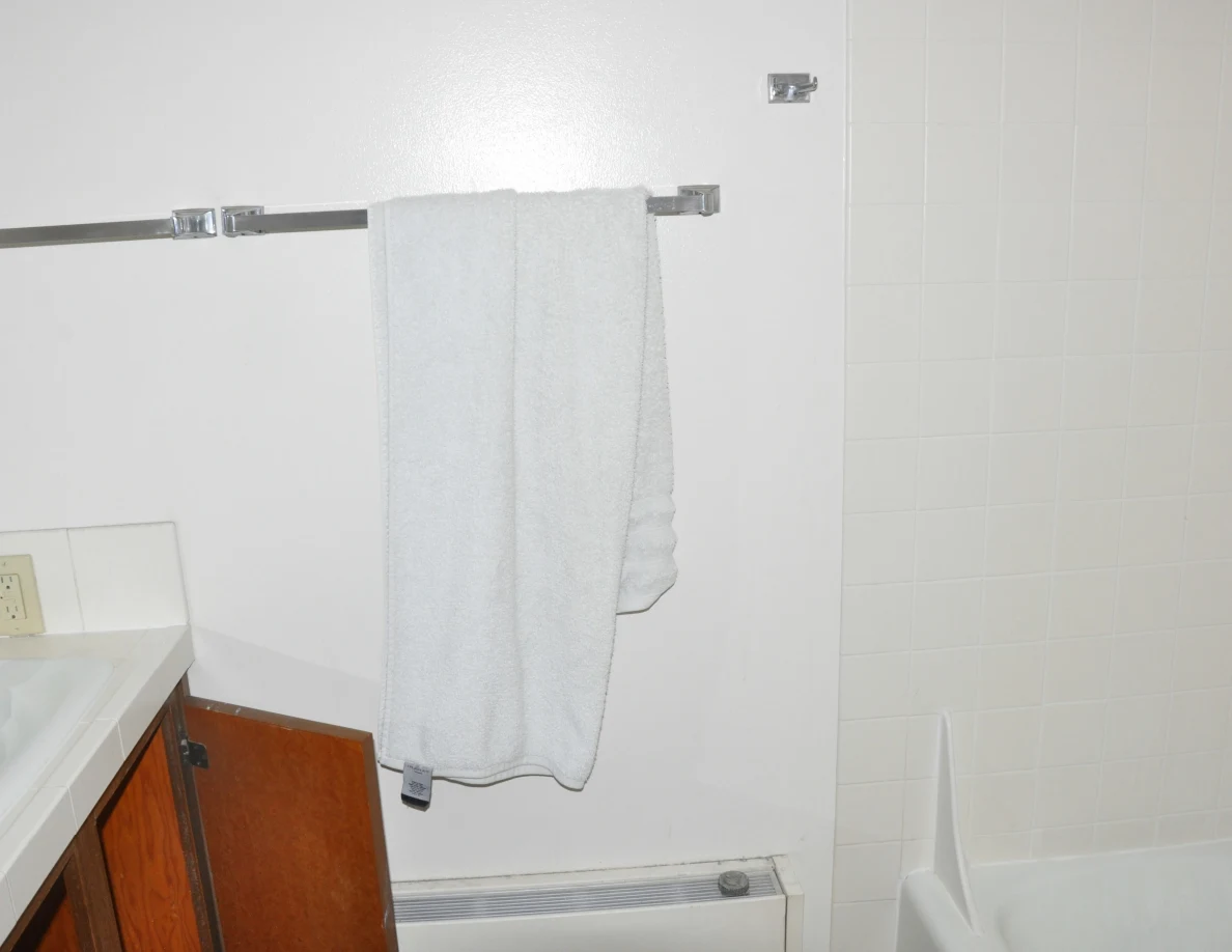 Gray towel on a wall bar above a heater beside a bathtub.
