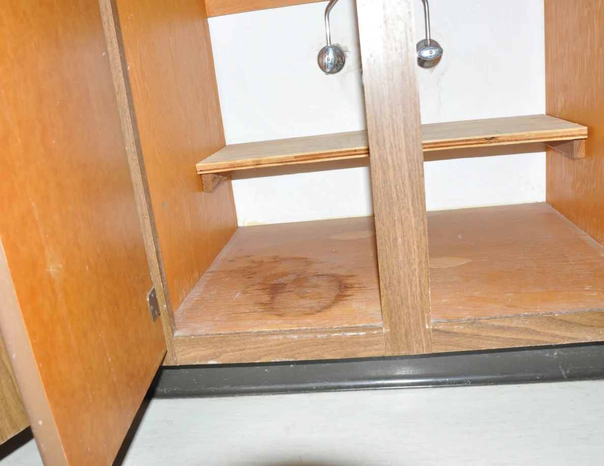 Lower under-sink cupboard with a circular brown mark on the wooden base.
