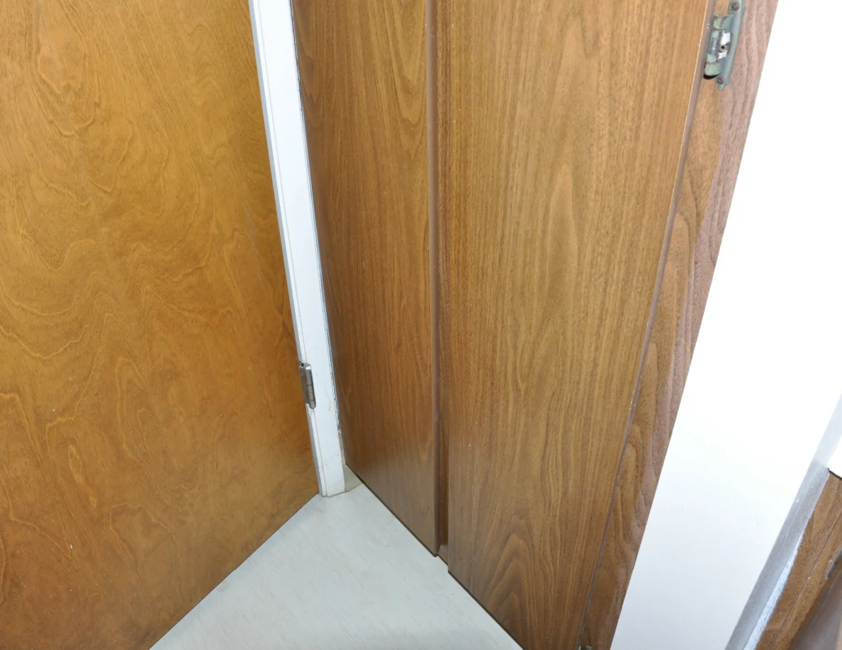 Lower wooden storage cabinet doors beside an open bathroom door.