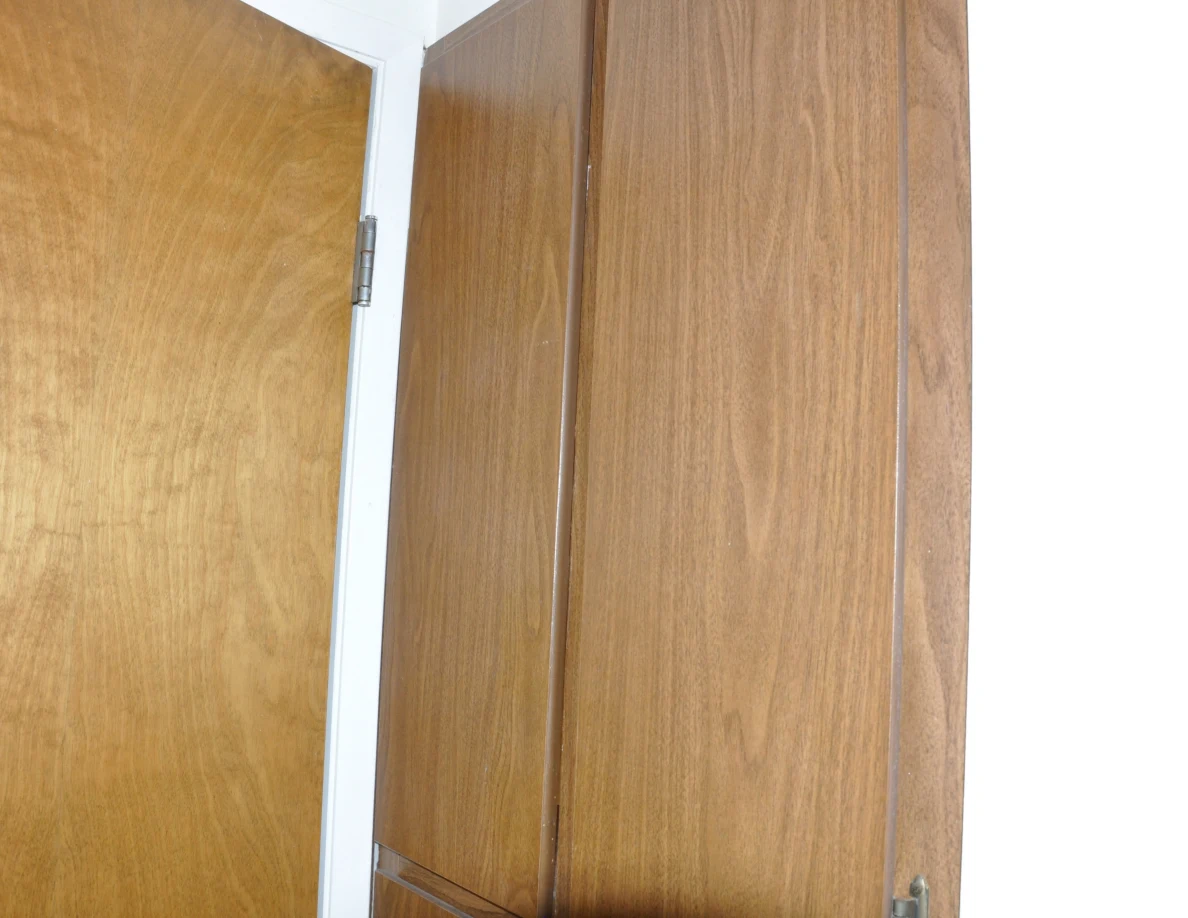 Upper wooden storage cabinet doors beside an open bathroom door.