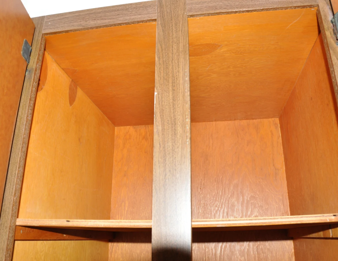 Empty upper interior of an open wooden cupboard.