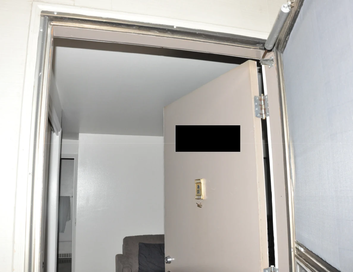 Open exterior doorway with storm door and a black redaction over part of the inner door.