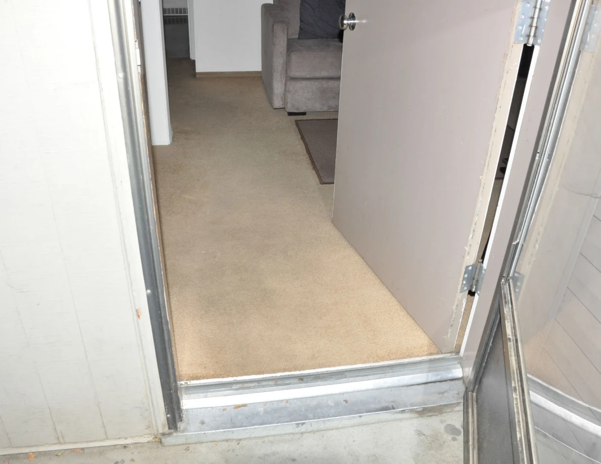 Entrance threshold leading onto beige carpet, with an armchair visible inside.