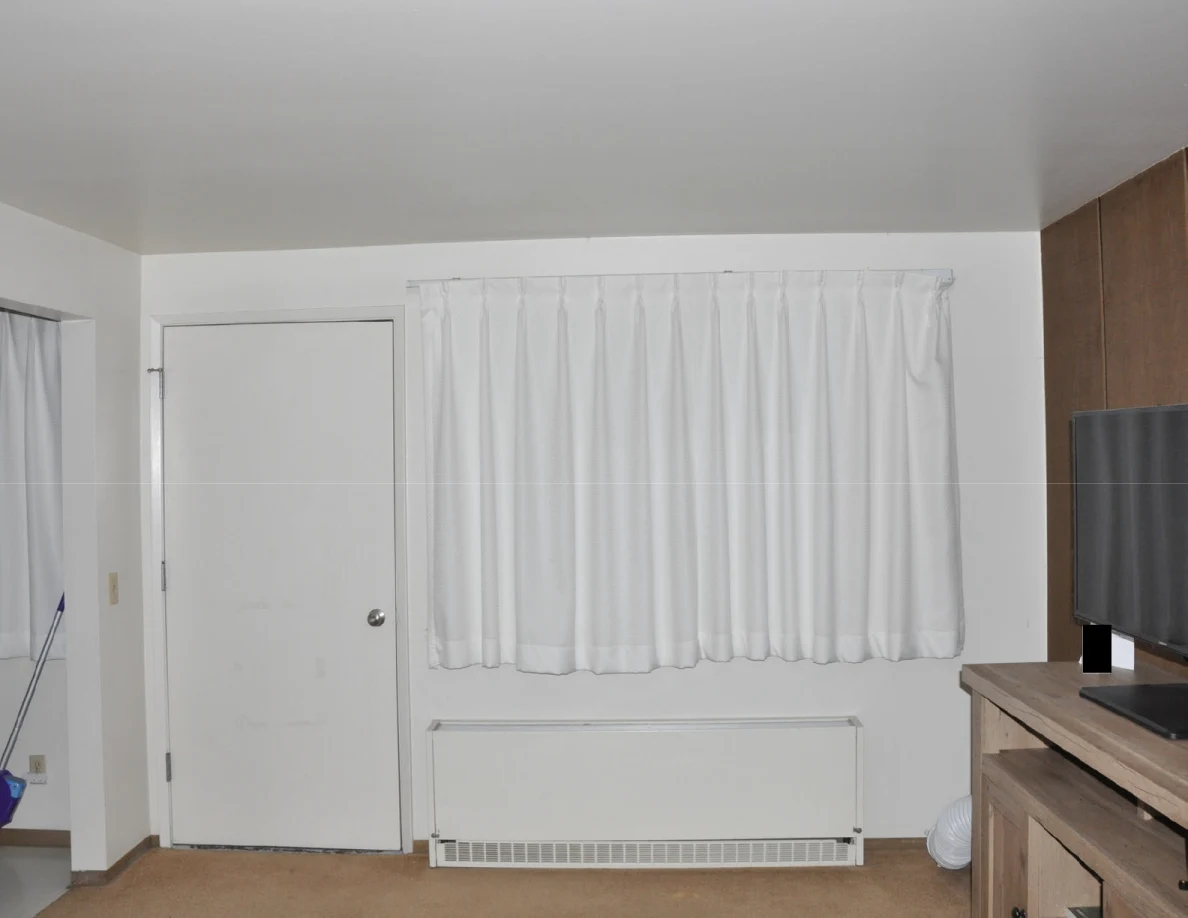 Living room wall with closed white curtains, a white door and wall heater.