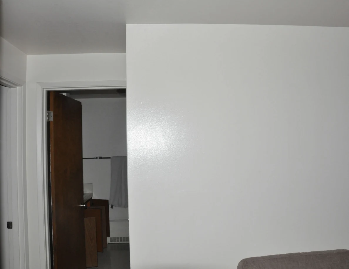 White wall beside a bathroom doorway, with a gray towel visible beyond.