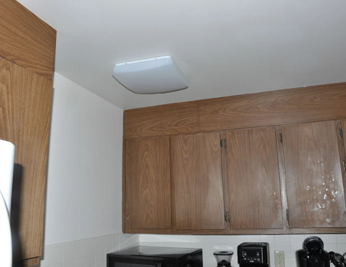 Kitchen ceiling light above upper wooden cabinets.