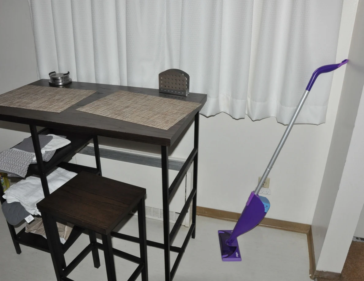 Tall dining table with two placemats, stools and a purple mop.