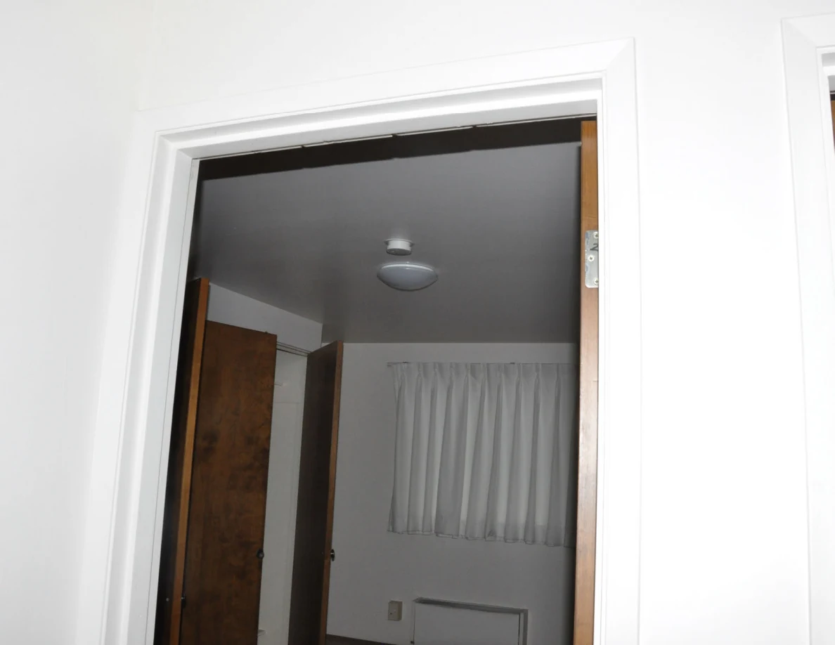 Upper doorway framing a ceiling light, curtains and open closet.